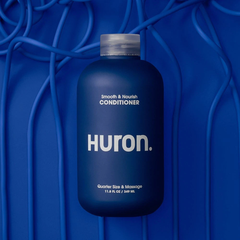 A bottle of conditioner lies against a dark blue background. 